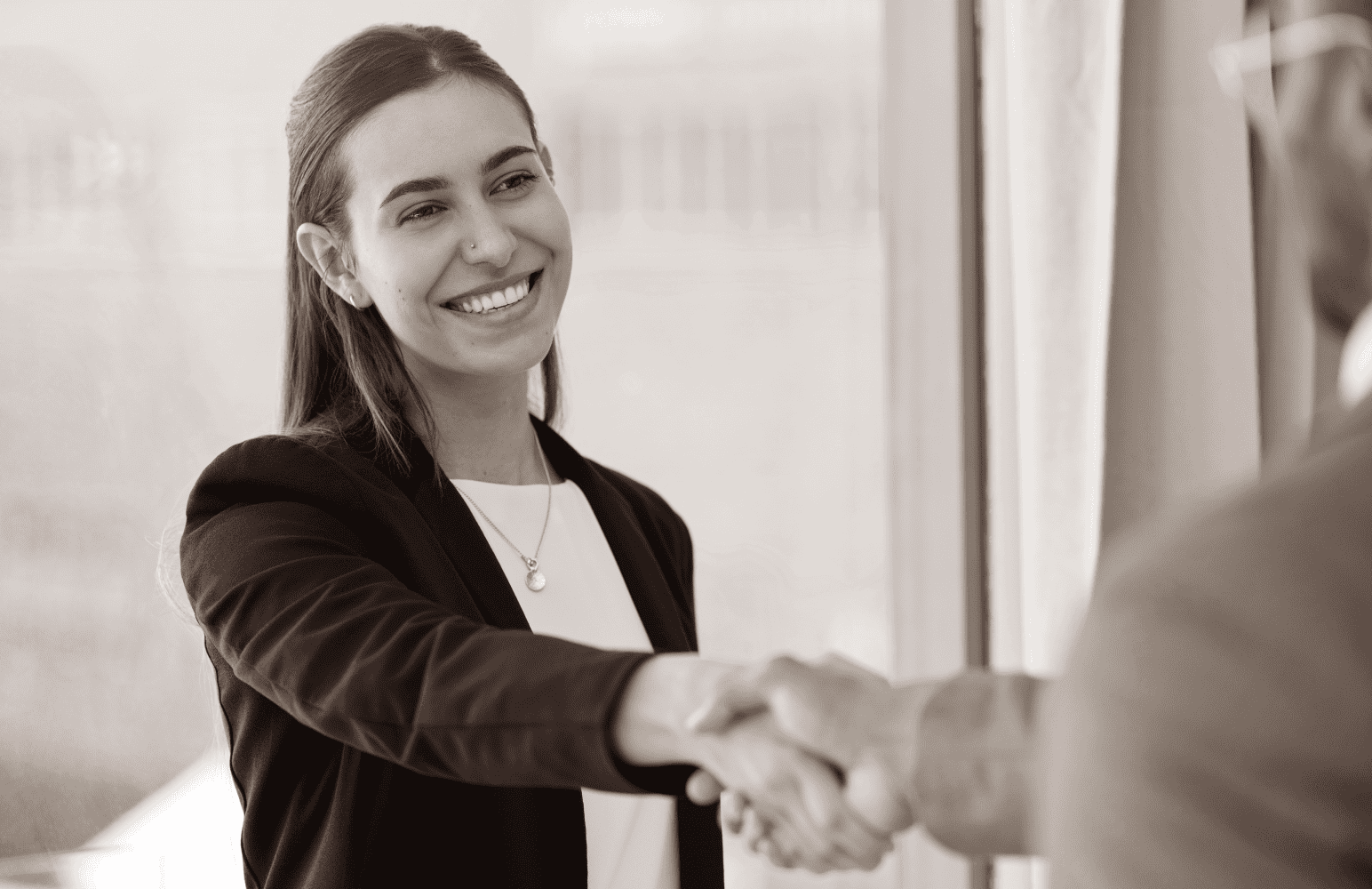 A woman shakes an outstretched hand. An example of best practices in executive recruitment.